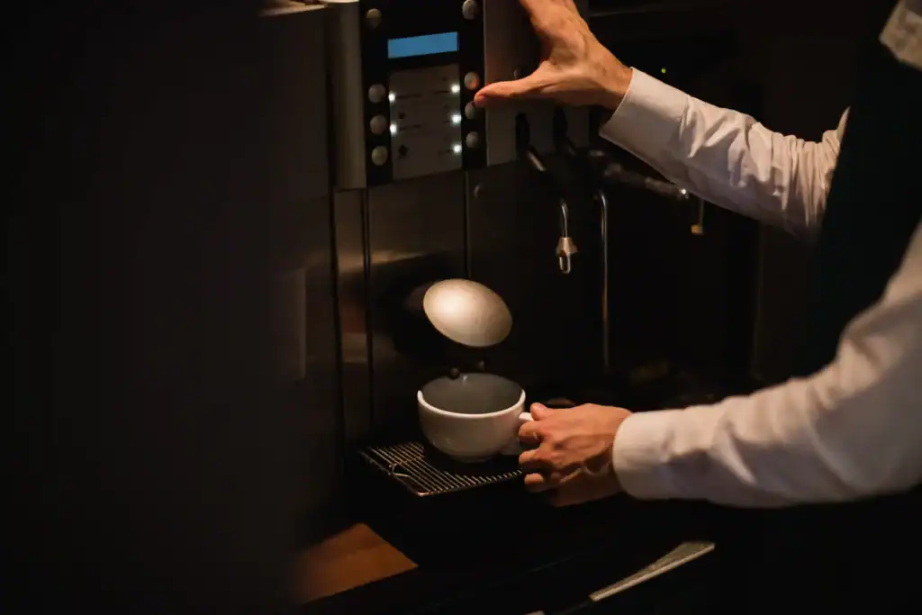 Mann som lager seg god og sunn kaffe ved bruk av kaffemaskin
